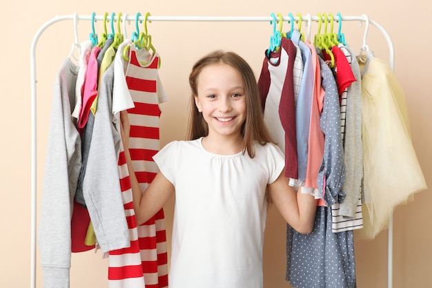 Schattig vrolijk meisje kiest kleding met vloerhangers