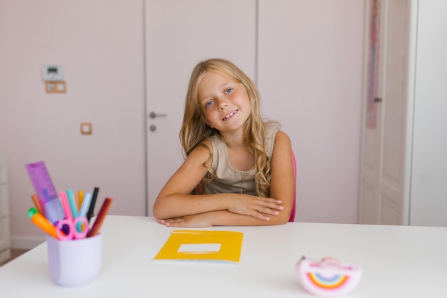 Schattig zevenjarig meisje zit aan een bureau in een klaslokaal op school