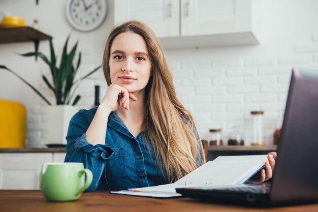 Schattig zwanger meisje een freelancer thuis werken in de keuken in de modus van zelfisolatie in quarantaine