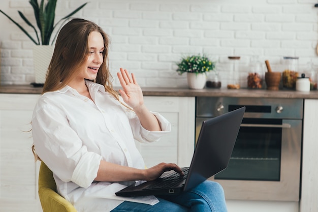 Schattig zwanger meisje een freelancer thuis werken in de keuken in de modus van zelfisolatie in quarantaine