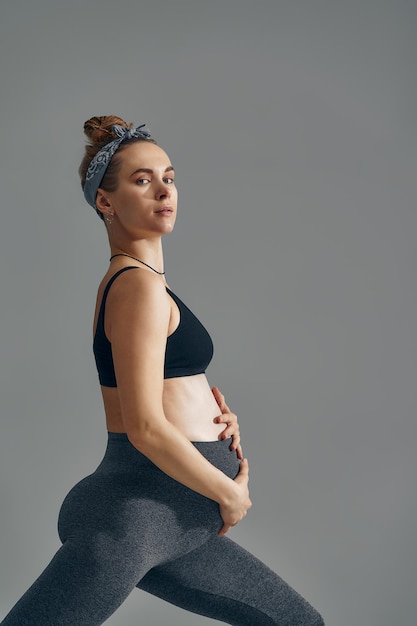 Schattig zwangere buik geïsoleerd op grijs Zijaanzicht van jonge zwangere vrouw omarmen haar buik met handen Grote buik op het derde trimester van de zwangerschap close-up Concept van het zwangere leven