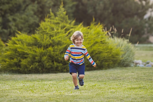 Schattige actieve en positieve babyjongen veel plezier en rennen in groen park