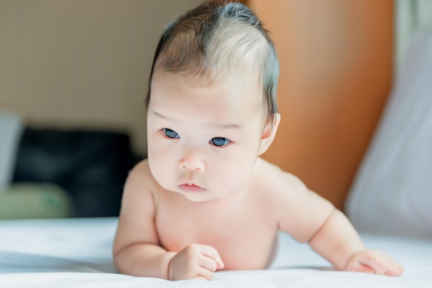 Schattige Aziatische baby liggend op het bed vanuit fronthoek