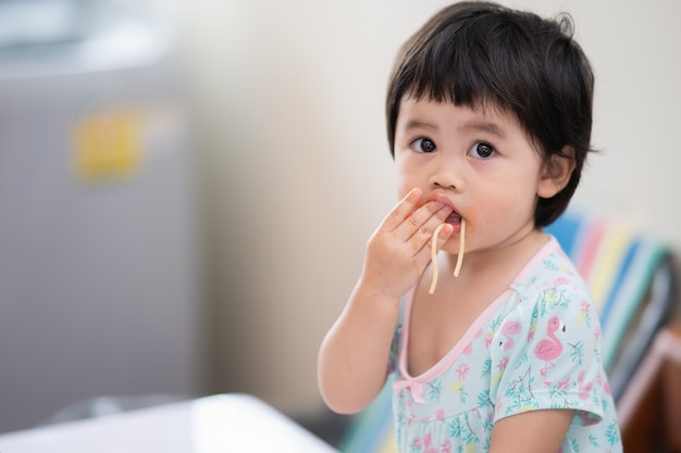 Schattige aziatische baby spaghetti eten in de eetkamer