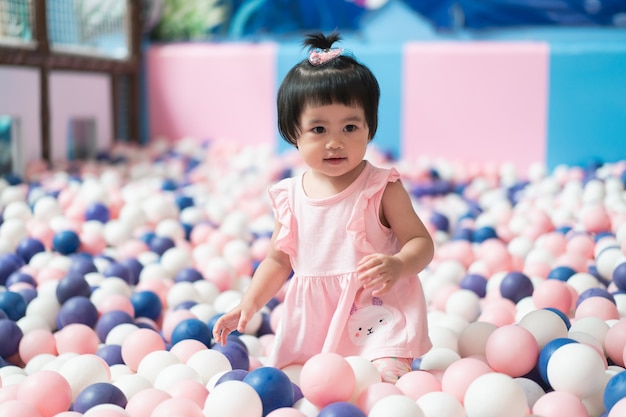 Schattige Aziatische baby spelen met veel ballen