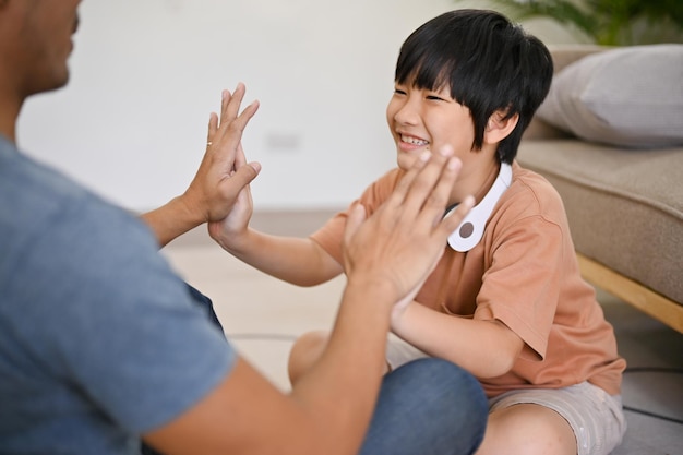 Schattige aziatische kleine jongen die met zijn vader speelt en leuke familiespelletjes doorbrengt in de woonkamer