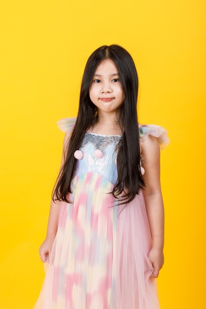 Schattige Aziatische vrouwelijke jongen, op een aantrekkelijk geïsoleerd portret van een jonge mannequin, glimlacht trots als tevreden over vrij gezond haar en gelukkig met een elegante draagstijl van een mooie mouwloze meisjesjurk.