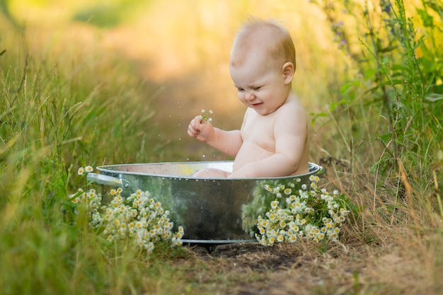 Schattige baby baadt in een ijzeren bassin in de tuin, buitenwaterbehandelingen, levensstijlruimte voor