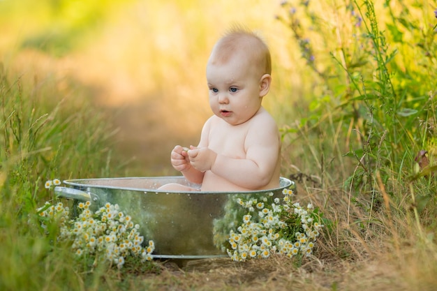 Schattige baby baadt in een ijzeren bassin in de tuin buitenwaterbehandelingen