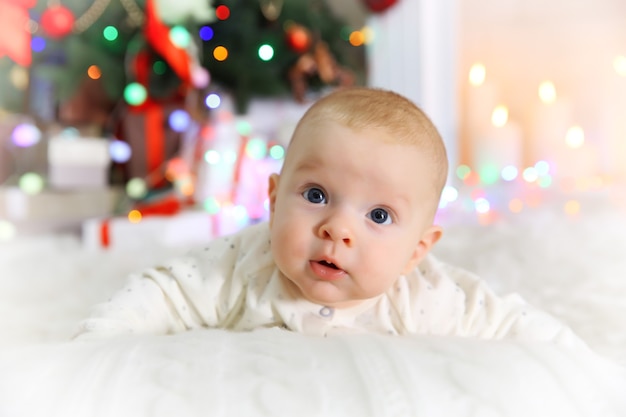 Schattige baby bij open haard en kerstboom thuis