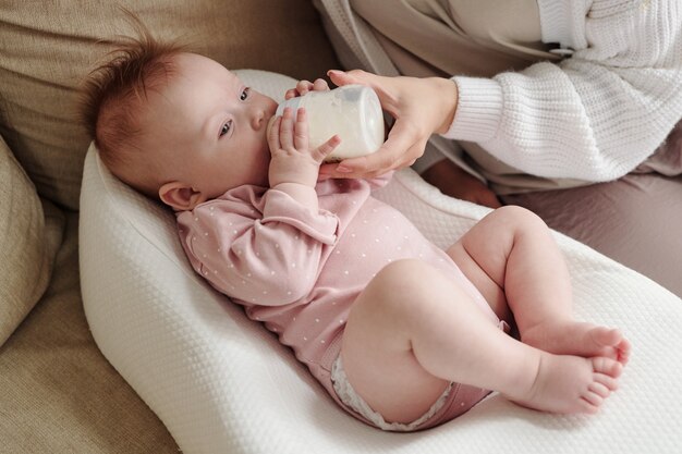 Schattige baby die melk eet uit de fles die door mama wordt vastgehouden