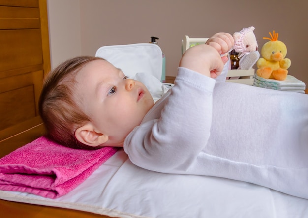 Schattige baby die met een kinderkam speelt na het verschonen van de luier