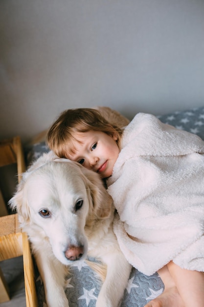 Schattige baby en zijn labrador retriever thuis op het bed