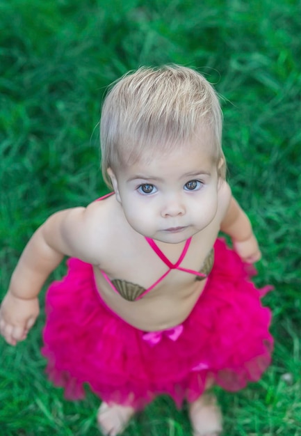 Schattige baby in een badpak gemaakt van schelpen zonnebaadt op het gazon