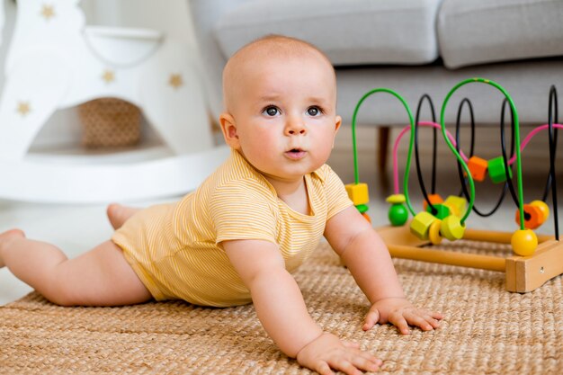 schattige baby in een gele bodysuit speelt met een educatief speelgoed