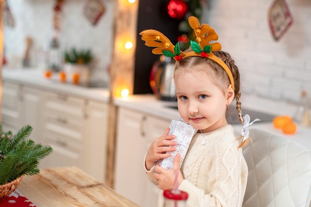 Schattige baby in een lichte trui en haarband met rendierhoorns