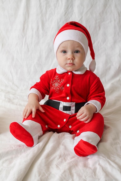 Schattige baby in kerstkostuum zit op een wit laken
