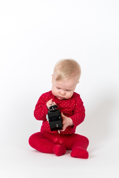 Schattige baby in rode outfit spelen met een klok