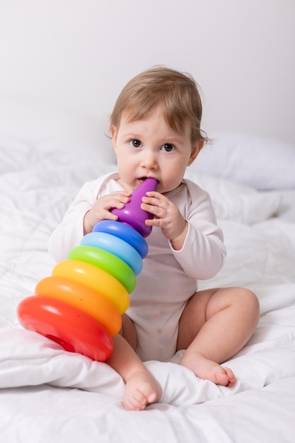 schattige baby in wit overhemd spelen met kleurrijk speelgoed op bed bannerkaart