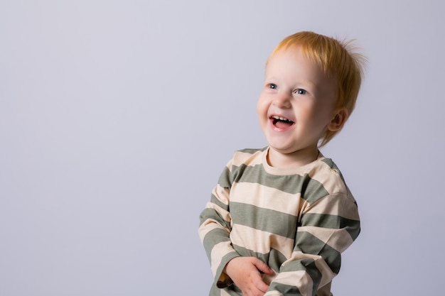 Foto schattige baby jongen van 3 jaar op een witte achtergrond lachend rood haar