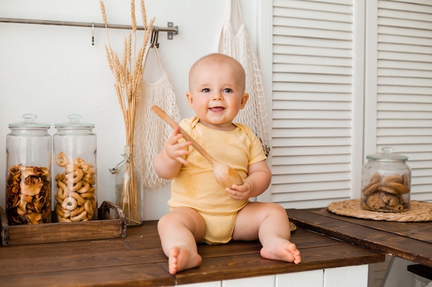 schattige baby kleine kok in een gele bodysuit zit in de keuken