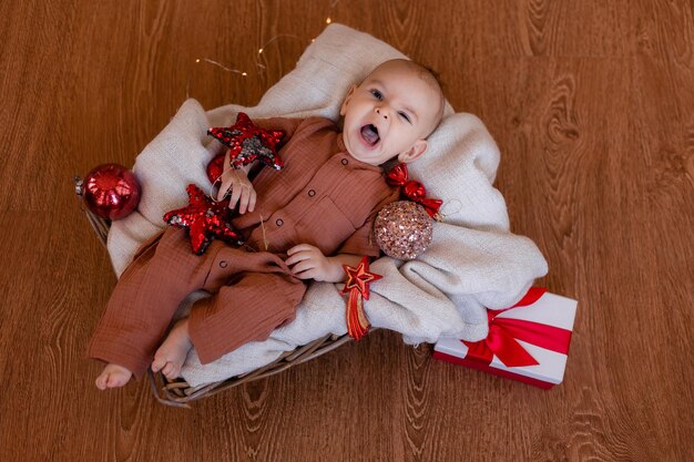 Schattige baby ligt in een deken op de vloer tussen kerstboomspeelgoed. winter, nieuwjaar. hoge kwaliteit foto