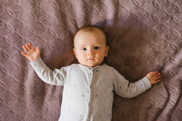 Schattige baby ligt op zijn rug op het bed