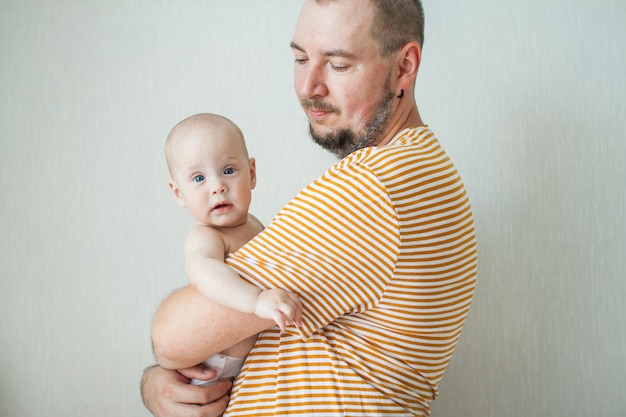 Schattige baby op de armen van zijn grote sterke vader.