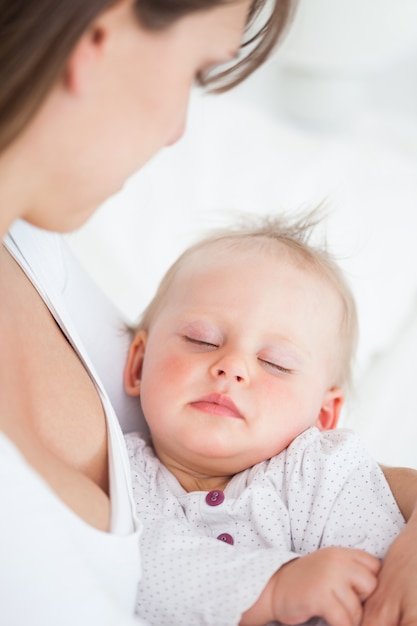 Schattige baby slaapt in de armen van haar moeder