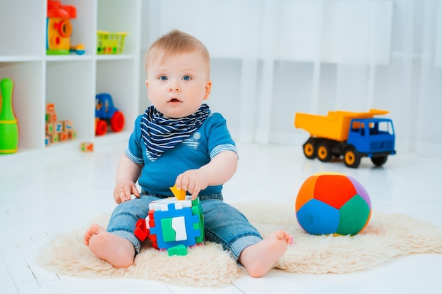 Schattige baby zit op de vloer van het huis te spelen met kleurrijk educatief speelgoed