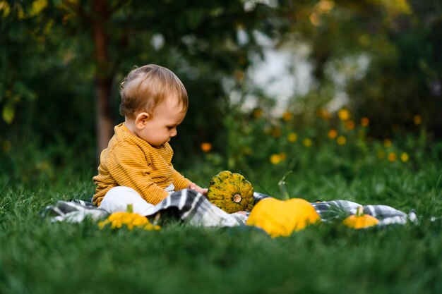 schattige baby zittend in het gras met groentenoogst