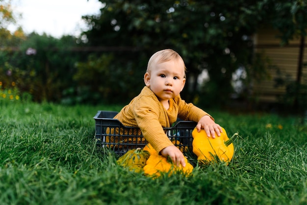 Foto schattige baby zittend in het gras met groentenoogst