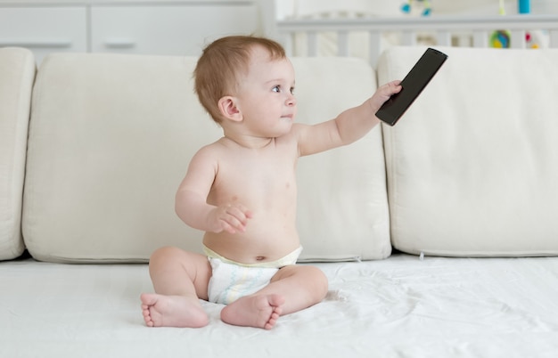 Schattige baby zittend op bed en spelen met smartphone