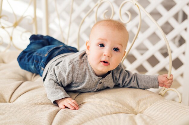 Schattige babyjongen in zonnige slaapkamer