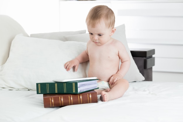 Schattige babyjongen met behulp van digitale tafel liggend op stapel boeken. Concept van baby-educatie