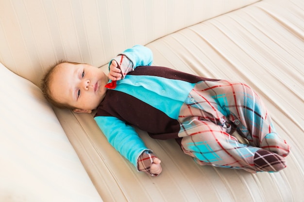 Schattige babyjongen met rood haar en blauwe ogen. Pasgeboren kind lyling in de bank.