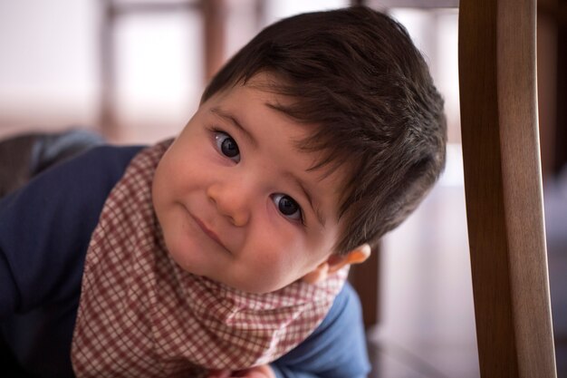 Schattige babyjongen onder de tafel kijken naar de camera.