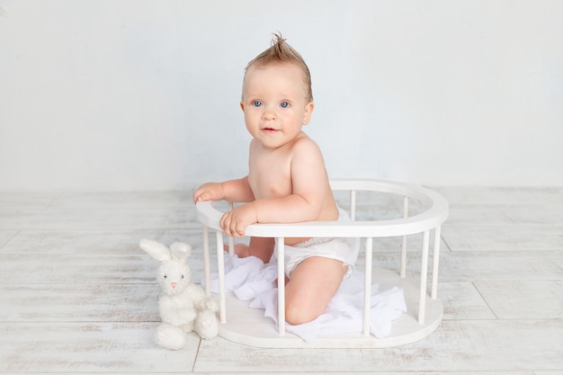 Schattige babyjongen op een witte achtergrond met een kapsel en grote blauwe ogen in luiers op een witte achtergrond met een kapsel zittend in een houten mand