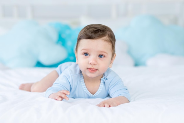 Schattige babyjongen op het bed voor het slapen van een gezonde, gelukkige kleine baby in een blauwe bodysuit