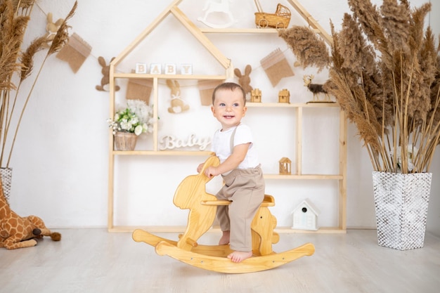 Schattige babyjongen rijdt op een houten schommelhaas in de kinderkamer thuis educatief speelgoed voor kinderen