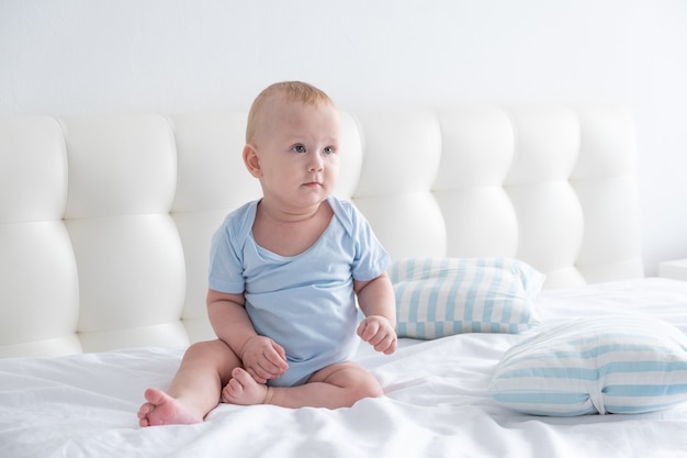 Schattige babyjongen thuis in het bed zitten. beddengoed voor kinderen.