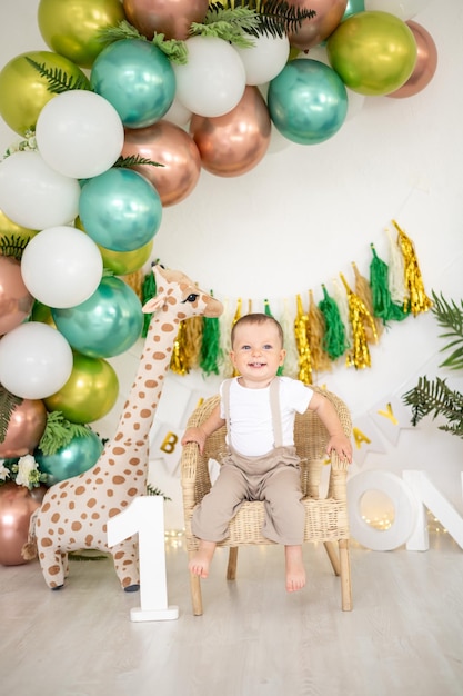 Schattige babyjongen viert zijn eerste verjaardag op de achtergrond van heldere kleurrijke ballonnen en feestelijke rekwisieten de eerste kindervakantie