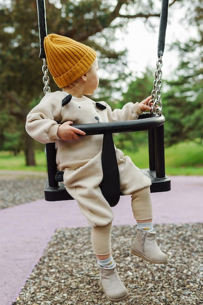 Schattige babyjongen zittend op een schommel in openbaar park