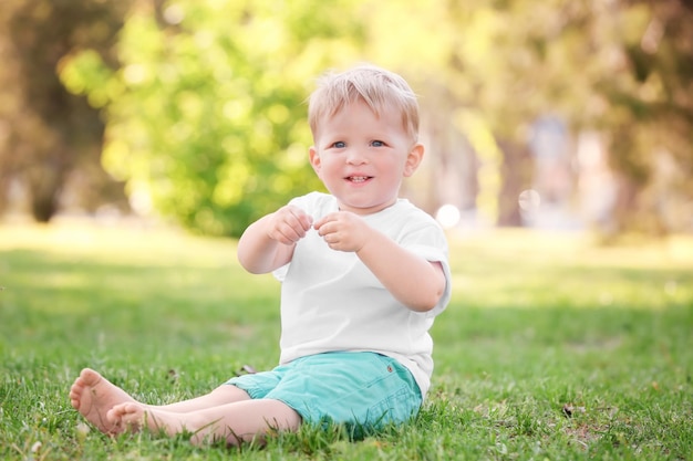 Schattige babyjongen zittend op groen gras in park