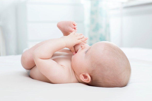 Schattige babymeisje liegen en haar been in haar mond trekken