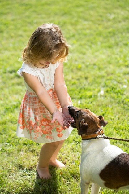 Schattige babymeisje met russell terrier hond op groen gras in de zomer grappig klein kind op de natuur happ