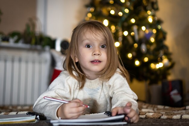 Schattige babymeisje schrijft een brief aan de kerstman