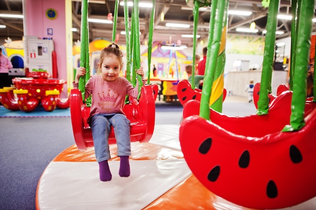 Schattige babymeisje swingen op schommels in indoor speelcentrum.