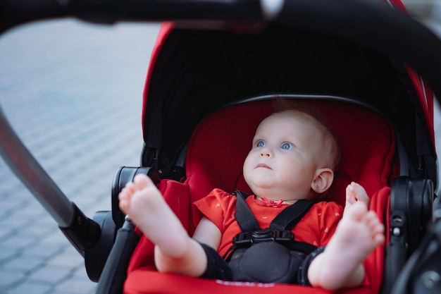 Schattige babymeisje zit in rode kinderwagen