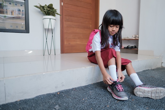 Schattige basisschoolleerling doet haar schoenen aan